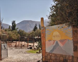 a gate with a painting of a face on it at Gran Casa Hostel&Camping in Tilcara