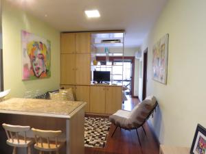 a living room with a kitchen with a bar and chairs at Kitnet Canela Plaza Serrana in Canela +9 photos