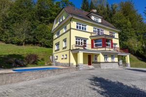 una casa amarilla con una piscina frente a ella en Villa Weber Apartments, en Albrechtice v Jizerských horách