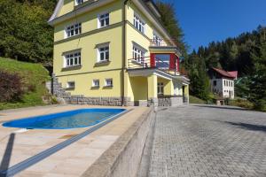 una casa amarilla con piscina frente a ella en Villa Weber Apartments, en Albrechtice v Jizerských horách