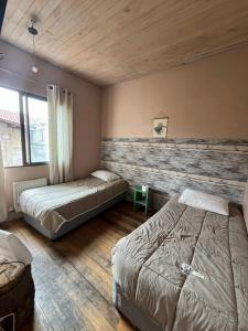 a bedroom with two beds and a wooden wall at Hotel Nativo in Santiago