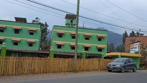 a car parked in front of a green building at Hotel COMTUCAR in Carhuaz