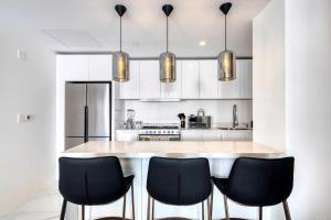 a kitchen with a large island with black chairs at Lumina at Marea Cabo San Lucas in Cabo San Lucas