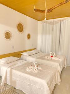 two beds in a room with white sheets at Meu Paraíso Flats in Maragogi