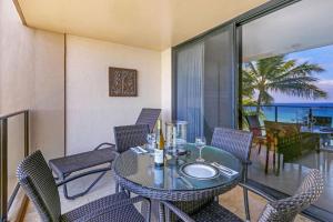 Un comedor con una mesa de cristal y sillas. en Mahana 617, en Kahana