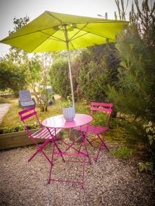a pink table and two chairs with an umbrella at Grand appartement au calme in Lérouville