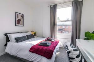 a bedroom with a bed with a pink blanket and a window at Kasu Lodge - Radford, Nottingham in Nottingham