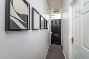 a hallway with a black door and pictures on the walls at Kasu Lodge - Radford, Nottingham in Nottingham