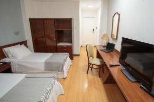 a hotel room with a bed and a desk with a television at Fast10 City Hotel - Cais Embarcadero, Mercado Público, Parque Harmonia in Porto Alegre