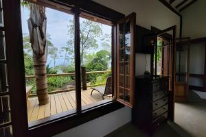 ein Zimmer mit großem Fenster und Holzterrasse in der Unterkunft Bangalô com vista e piscina natural em Flechas in Ilhabela