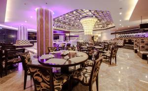 un ristorante con tavoli e sedie con illuminazione viola di Army Hotel a Hanoi