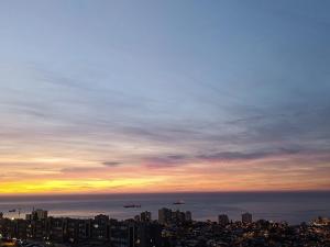 a city skyline at sunset with planes in the sky at Hostel Agua Santa Habitaciones Vista al Mar in Viña del Mar