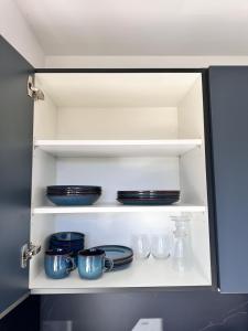 a cupboard with plates and dishes on it at STUDIO HORIZON - SEA VIEW - POOL- Air Conditioner - Kitchen - Wifi -TV Train - Bus - in Villeneuve-Loubet