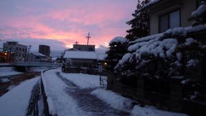 a snow covered street with a sunset in the background at Matsumoto BackPackers in Matsumoto
