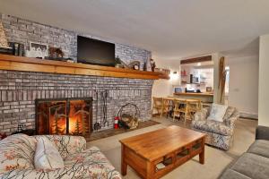 a living room with a fireplace with a tv above it at Sunrise Timberline M1- Cozy 2 BR Ski On Ski Off Condo in Killington