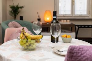 a table with a bowl of fruit and a bottle of wine at Casa Sancarlino - 200mt Clinica Zucchi in Monza