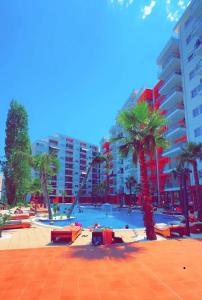 a pool with palm trees and a large building at Princ Apartment studio in Shëngjin