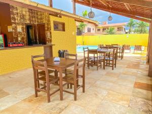 a restaurant with wooden tables and chairs and a pool at Hotel Sunshine Centro Cumbuco in Cumbuco