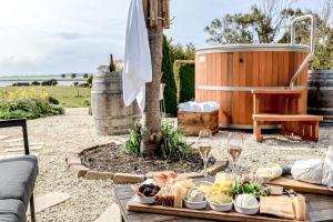 a table with food and wine glasses and a tub at Petite Chateau Waterfront chateau with Hot Tub in Clarence Point