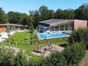 a building with a swimming pool in a garden at Waterside Luxury Sky Pad in Antoing