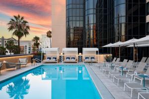 长滩Marriott Long Beach Downtown的一张酒店游泳池的图片,游泳池配有躺椅