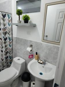 a bathroom with a white toilet and a sink at Casa Villa El Escape en Residencial Villa Panamericana in San Miguel