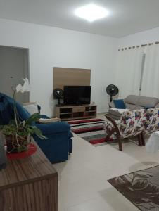un salon avec un canapé bleu et une télévision dans l'établissement Morada da praia, à Bertioga