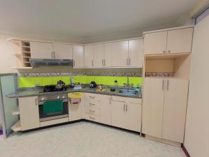 a kitchen with white cabinets and a green wall at Departamento en el Centro con Garaje in Loja +16 photos