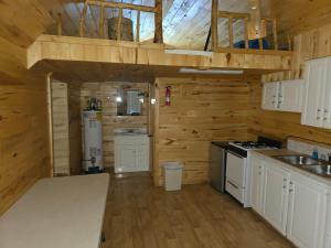 a kitchen with white cabinets and a stove top oven at Lake log Cabin getaway in Verdure