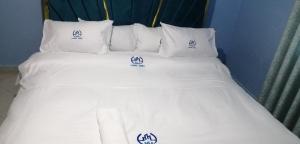 a white bed with white pillows and logos on it at NM Luxury Homes in Nakuru