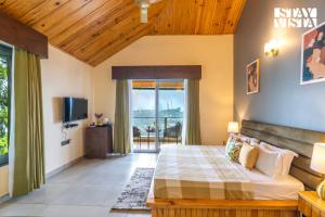 Un dormitorio con una cama y un televisor en una habitación. en StayVista at The Rasa Bungalow with Lake View, Wi-Fi, en Bhimtal