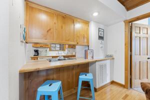 ブランソン・ウェストにあるParadise Lodge Homeのキッチン(木製キャビネット、青いスツール2脚付)