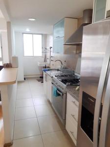 a kitchen with stainless steel appliances and white tile floors at Departamento a 2 min del museo Soumaya in Mexico City