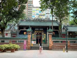 Una donna in piedi di fronte a un palazzo di 香港榆臨賓館 Yulam Guesthouse a Hong Kong