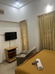 a bedroom with a bed and a chair and a television at Abids Inn Homestay in Bangalore
