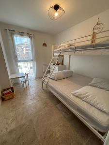 sypialnia z dwoma łóżkami piętrowymi i oknem w obiekcie Appartement T3 dans maison neuve 7 couchages w mieście La Seyne-sur-Mer