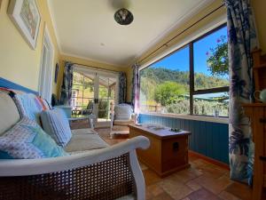 ein Wohnzimmer mit Couch und großem Fenster in der Unterkunft Kahurangi Cottage Wilderness Retreat in Stanley Brook + 8 Fotos