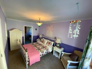 ein Schlafzimmer mit lila Wänden und einem Bett und einem Stuhl in der Unterkunft Kahurangi Cottage Wilderness Retreat in Stanley Brook