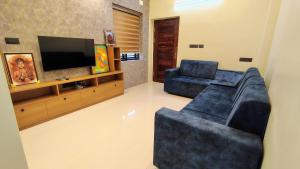 a living room with a couch and a flat screen tv at HRISHI Guest Suites 3Bhk in Trivandrum
