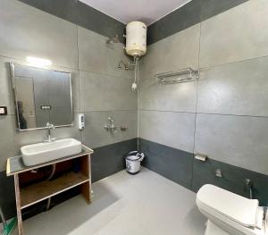 un bagno con lavandino, WC e specchio di The Pahadi House a Shimla