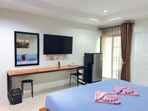 a bedroom with a bed and a desk with a television at The Gun Hotel Premium in Surin