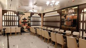 a dining room with tables and chairs and windows at Hotel Ranjeet Akola in Akola