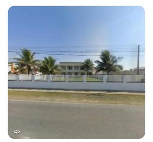 a white fence with palm trees in front of a building at Pousada da Ely in Navegantes
