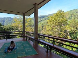 a man sitting on a porch looking out at the mountains at โฮมเสตย์ลาบา1 in Ban Musoe La Ba
