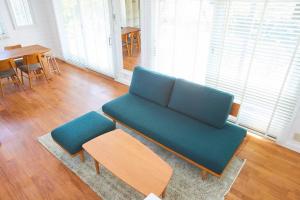 a living room with a blue couch and a table at jfハウス - カフェ併設の一棟貸切で楽しむプライベートステイ - サーフポイントまで徒歩5分 in Ichinomiya