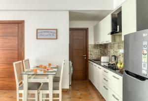 a kitchen with a table and a refrigerator at Radiant 1BHK Apartment by tisyastays in Candolim