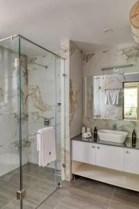 a bathroom with a glass shower and a sink at Radiant 1BHK Apartment by tisyastays in Candolim