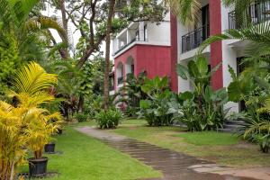 a garden in front of a red and white building at Radiant 1BHK Apartment by tisyastays in Candolim