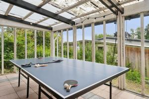 a ping pong table in a room with windows at Seaside Hotel Atmosphere 100 Meters From The Sea in Strøby Egede
