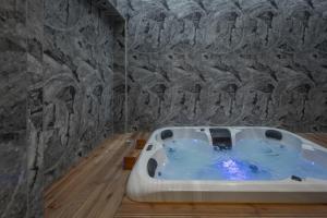 a bath tub in a bathroom with a stone wall at Royal Gold City Suites by Omilos Hotels in Heraklio